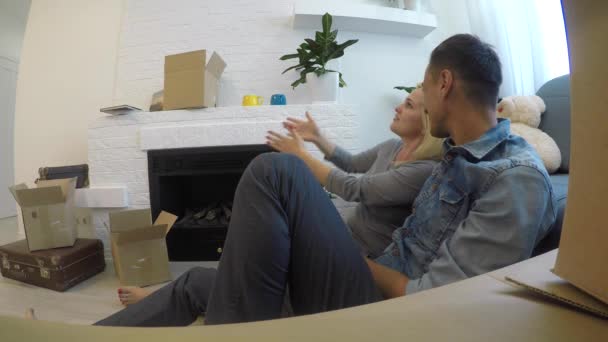 junges Paar diskutiert Ideen, während es zu Hause auf dem Boden am Kamin sitzt