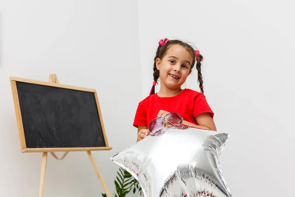 Fröhliches Kleines Mädchen Hält Sternförmigen Ballon Mit Brett Auf Dem — Stockfoto
