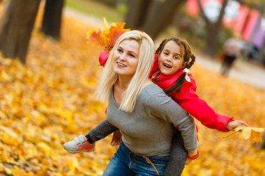 Anne ve kızı sonbahar sarı parkta eğleniyor