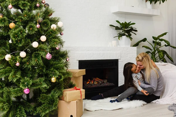 母亲与女儿女儿女儿女儿坐在客厅附近的壁炉和圣诞树的地板上 — 图库照片
