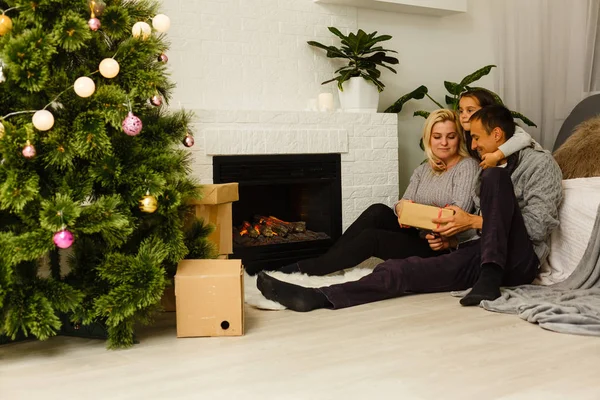 現在リビングのクリスマス ツリーの近くの床に座っていると家族 — ストック写真