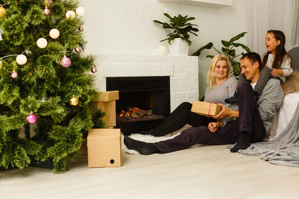 現在リビングのクリスマス ツリーの近くの床に座っていると家族 — ストック写真