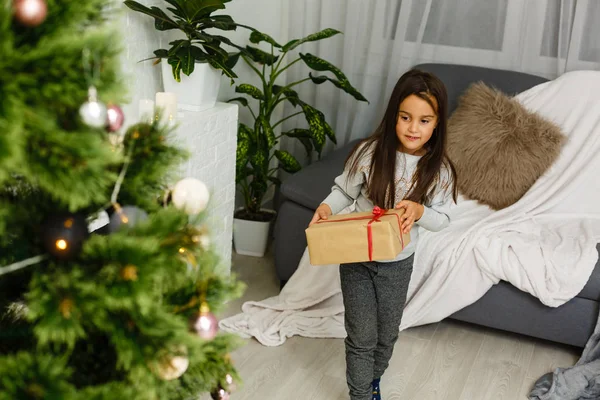 ギフト ボックス クリスマス ツリーの横に立っている幸せな女の子 — ストック写真