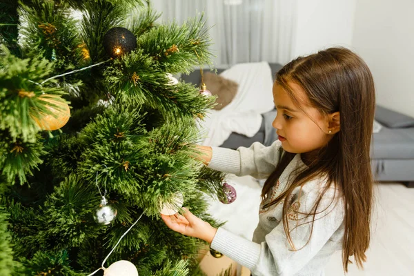 スタイリッシュなリビング ルームでクリスマス ツリーを飾る少女 — ストック写真