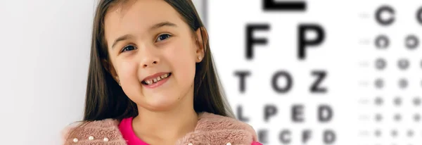 視力検査の子 光学店で眼鏡を選ぶ小さな子供 小学生の視力測定 子供用のアイウェア ドクター パフォーマンス アイチェック 女の子とともに眼鏡で手紙チャート — ストック写真