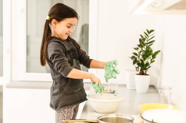 Küçük tatlı kız mutfakta yemek pişiriyor. Kek ve kurabiye yaparken eğleniyorum. Gülümsüyor