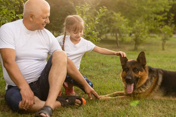 Abuelo con nieta y un perro en el jardín — Foto de Stock