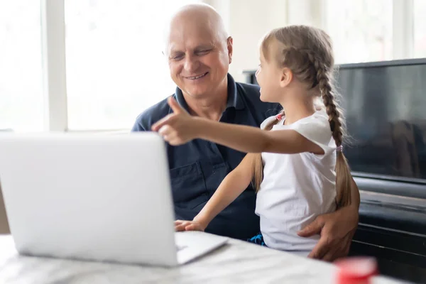 Portrait de grand-père et petite-fille faisant des devoirs avec ordinateur portable. — Photo