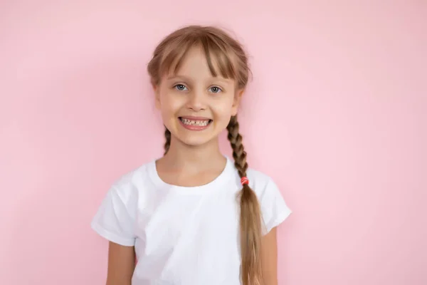 ピンクの背景に笑みを浮かべて白いTシャツのかわいい女の子 — ストック写真