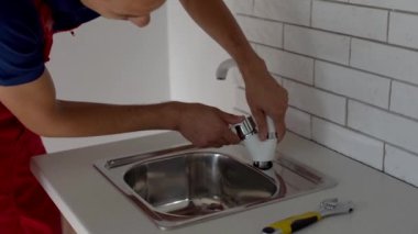 Üniformalı profesyonel bir tesisatçı, vincin mutfağa yerleştirilme kalitesini garanti eder. Mutfak lavabosunun üzerine yeni bir musluk kuruyorum.