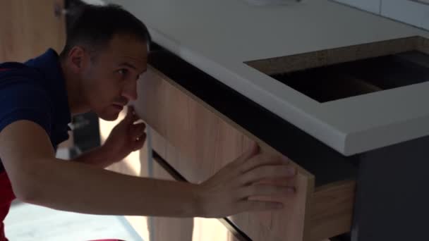 Κοντινό πλάνο του αρσενικού ξυλουργού χέρια συναρμολόγηση ντουλάπι επίπλων και την εγκατάσταση ξύλινων νέο συρτάρι. — Αρχείο Βίντεο