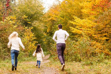 Sonbahar parkında güzel bir aile fotoğrafı, güzel bir kızı olan genç bir aile dışarıda oynuyor, sonbaharda arka bahçede eğleniyor, mutlu bir aile sonbaharda doğanın tadını çıkarıyor.