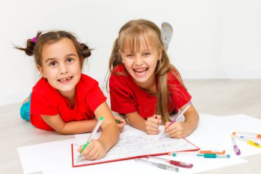 İki kız, beyazlar üzerinde kitap okuyor.