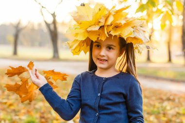 Sonbahar tatili. Sonbahar atmosferi. Gülümseyen sevimli okul kızı sonbahar yeşillik geçmişi. Keyfin yerinde. Mutlu çocuk. Ekim 'e hoş geldin. Doğayla bütünleşti. Küçük çocuk sonbahar parkında yürüyor..