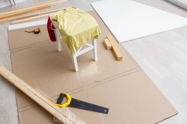 Yuvarlak masanın üzerinde tahta raflar ve dairenin balkonunda mobilya yapan yaşlı bir adam. Ev gelişimi