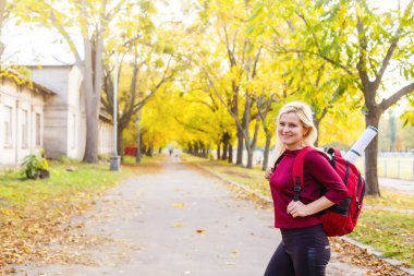 Sonbahar parkında sırt çantalı bir kız.