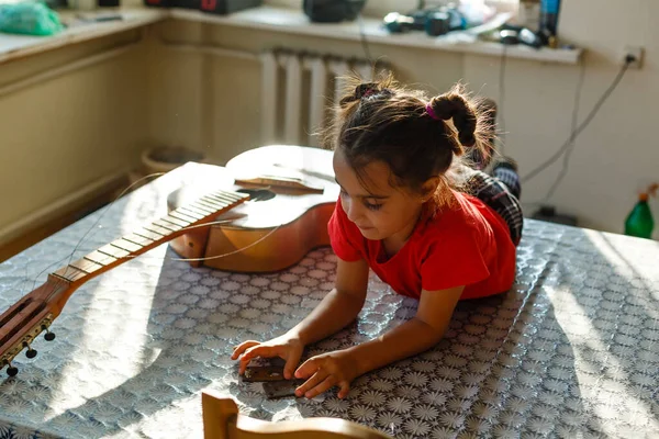 little girl holding a broken guitar, guitar repair