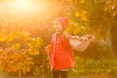 Elinde kitapla ilkokul öğrencisi. Açık hava binasının yakınında sırt çantalı bir kız. Dersler başlıyor. Sonbaharın ilk günü.