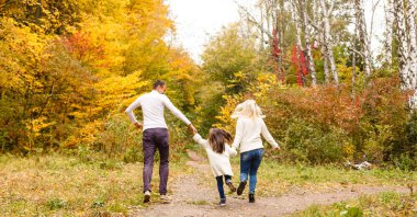 Sonbahar parkında güzel bir aile fotoğrafı, güzel bir kızı olan genç bir aile dışarıda oynuyor, sonbaharda arka bahçede eğleniyor, mutlu bir aile sonbaharda doğanın tadını çıkarıyor.