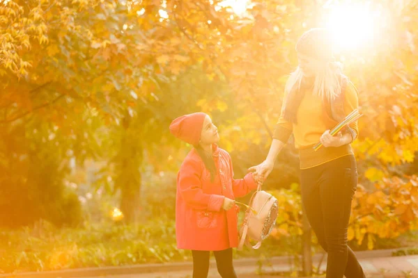 Parent take child to school. Pupil of primary school with backpack outdoors. Mother and daughter go hand in hand. Back to school. First day of fall. Elementary student. Kindergarten, preschool.