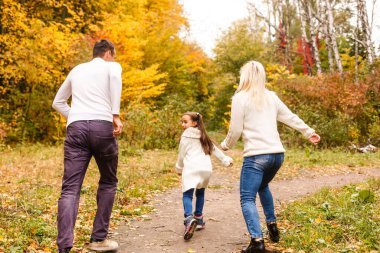 Sonbahar parkında güzel bir aile fotoğrafı, güzel bir kızı olan genç bir aile dışarıda oynuyor, sonbaharda arka bahçede eğleniyor, mutlu bir aile sonbaharda doğanın tadını çıkarıyor.