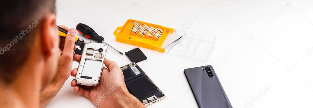 Repairman workplace with phone and special tools. Disassembled smartphone with disassembling instruments and repairer hands on white background. Electronics repair service, device production concept