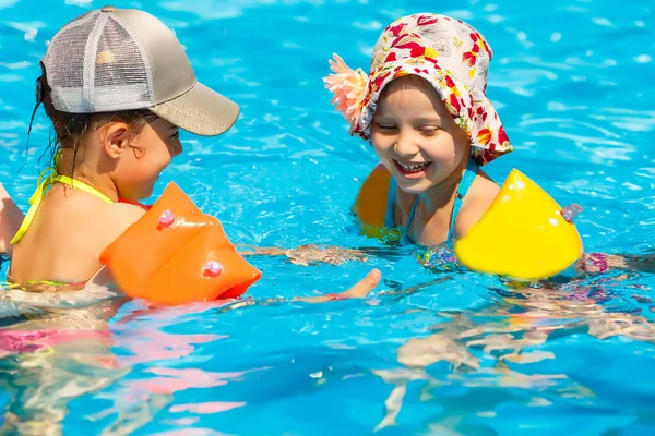 Dos mujeres y sus hijos en la piscina — Foto de Stock