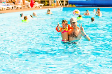 Baba yüzme havuzunda kızıyla oynuyor.