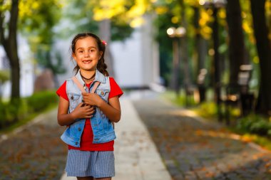 Sabahları küçük bir kız sıcak güneşin altında sırt çantasıyla okula gidiyor. Eğitim kavramı.