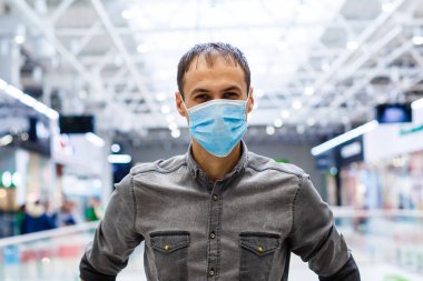 Alışveriş merkezinde maske takan genç bir adam. Maskeli adam kendini Çin virüsü salgınından koruyor 