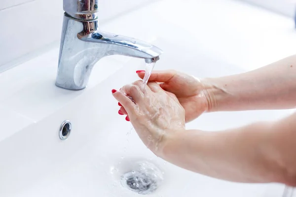 ステンレス製の水道水の下で石鹸で手を洗う女性白いセラミックの手の洗面台 健康管理と衛生の概念にタップ — ストック写真