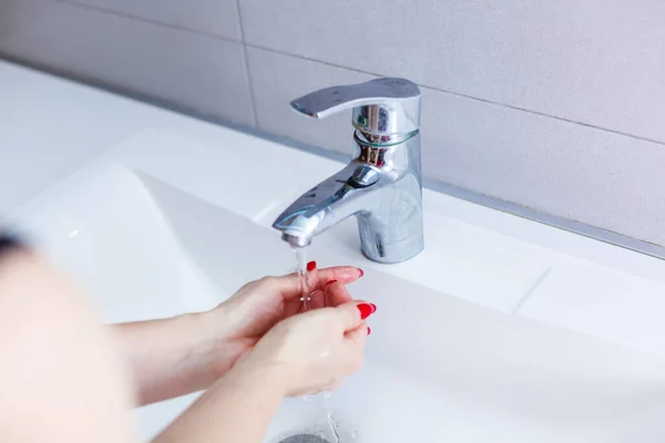 Washing woman hands with streaming water under tap in bathroom,washing hands in a white basin with a bar,Hygiene,Hand washing,Woman washing hands under a tap water