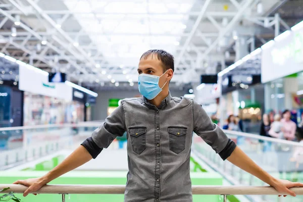 A young man in a medical mask in a shopping center. The masked man protects himself from the epidemic of the Chinese virus \