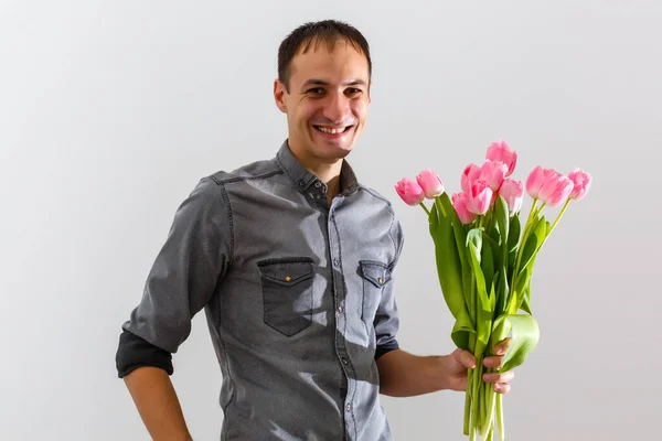 Man with flowers. Romantic Man with bouquet of tulips for birthday. Happy woman\'s day. Giving bouquet of flowers. Handsome man giving flowers. White background. Horizontal photo.s