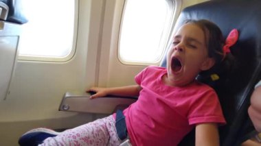 Uçakta oturan küçük bir kız.