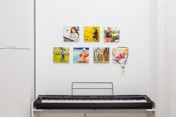Some photos hanging on a rope, white wall background, next is an electronic piano