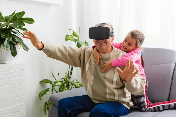 Kıdemli adam evde sanal gerçeklik gözlüğü takıyor.