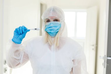 Tehlikeli madde koruma giysisi içindeki araştırmacı kimya laboratuarındaki bir deney tüpünü inceliyor..