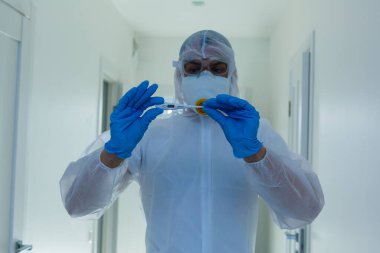Laboratuvarda kolları çapraz olan koruyucu teçhizat kullanan bilim adamı.