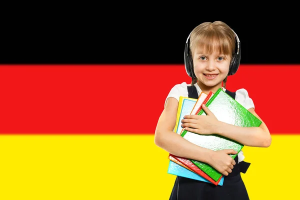 Happy young girl holding books, on the background of the flag of Germany. The concept of language learning and study. Travels.