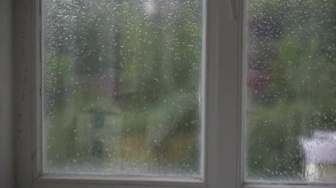 Pencereden yağmur yağıyor. Pencere yüzeyine düşen yağmur damlaları. Kimse.