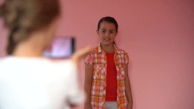 Pembe arka planda cep telefonuyla fotoğraf çeken çocuklar. Akıllı telefondan selfie çeken arkadaşlara yakın çekim..