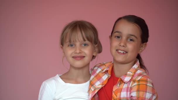 Niñas Sonrientes Hermanas Mejores Amigos Abrazan Sobre Fondo Rosa Los — Vídeo de stock