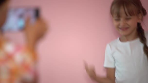 孩子们在粉色背景的手机上拍照 在智能手机上自私自利的朋友的亲密接触 — 图库视频影像