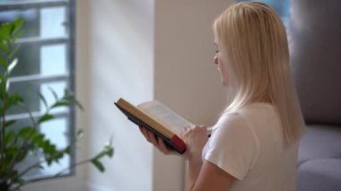 Elinde İncil tutarken dua eden genç bir kadın. İncil 'i olan bir kadın evdeki günlük ibadetinde Tanrı' ya dua ediyor. 4k