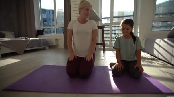 Anak perempuan keluarga yang bahagia dan ibu muda yang bahagia bersenang-senang melakukan latihan yoga bersama-sama, tersenyum hati ibu mengajar anak kecil yang lucu untuk bermeditasi sambil tertawa di rumah — Stok Video