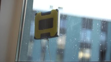 Modern robotik pencere temizleyicisi iş başında. Elektrikli süpürge robotu apartmanın penceresini temizliyor. Ev hizmeti ve temizlik konsepti. 4k video