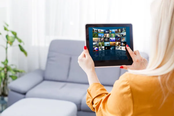 Mujer joven sentada cerca del sofá viendo vídeo en la tableta — Foto de Stock