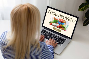Oturan kadını kapatın ve dizüstü bilgisayardan yemek siparişi verin. Kahve dükkanının, dijital pazarlama kavramının sepet işlevi web sayfasına ek olarak. Dijital yaşam tarzı.