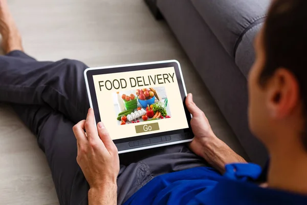 Mężczyzna Zamawiający Zabrać Jedzenie Przez Internet Tabletu Podczas Leżenia Domu — Zdjęcie stockowe